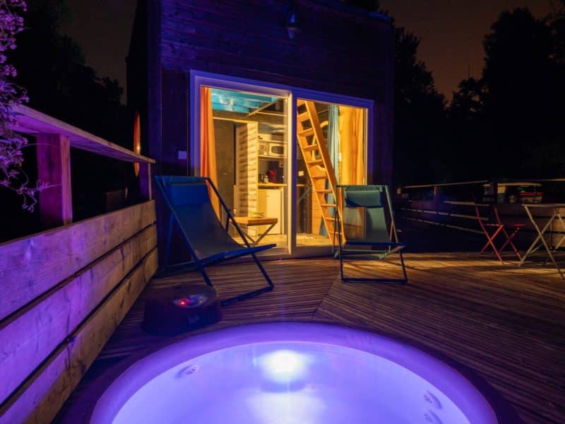Hébergement insolite à Champagne-Ardennes avec jacuzzi lumineux sur une terrasse en bois.