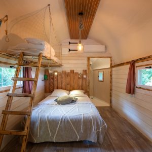 Cabane en bois avec lit double, échelle et ambiance chaleureuse à Champagne-Ardennes.