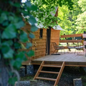 Cabane en bois à Champagne-Ardenne avec terrasse en bois et chaises modernes.