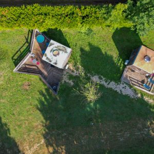 Hébergement insolite en cabanes avec terrasses en bois, entourées de verdure.