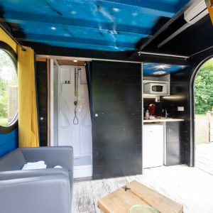 Hébergement insolite à Champagne-Ardenne : cabane colorée avec coin cuisine et douche.