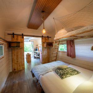 Hébergement insolite en bois à Champagne-Ardenne, avec lit suspendu et décoration naturelle.