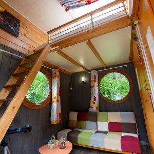Cabane insolite à Champagne-Ardenne, avec un intérieur coloré et des fenêtres rondes.