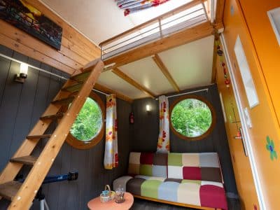 Cabane insolite à Champagne-Ardenne, avec un intérieur coloré et des fenêtres rondes.