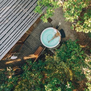 Cabane perchée en Midi-Pyrénées avec baignoire en bois entourée de verdure.