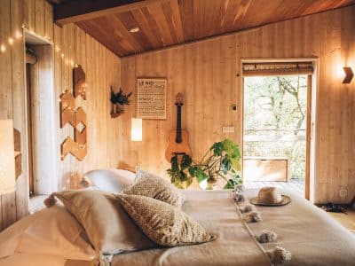 Hébergement insolite en Midi-Pyrénées : chambre en bois avec guitare et plantes.
