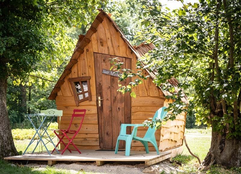 Cabane en bois à Champagne-Ardenne, avec terrasse et chaises colorées.