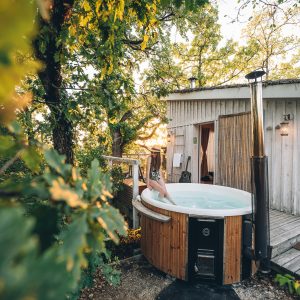 Cabane perchée en Midi-Pyrénées avec jacuzzi extérieur entouré de verdure.