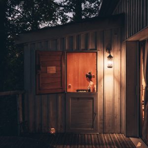 Cabane en bois perchée, éclairée par une lanterne, offrant une ambiance chaleureuse.
