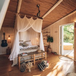 Hébergement insolite en Midi-Pyrénées : cabane en bois avec lit à baldaquin et terrasse.
