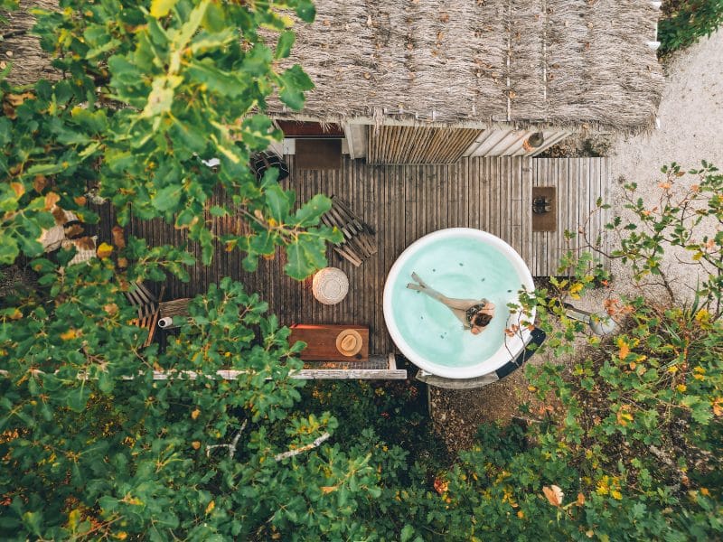 Cabane perchée en Midi-Pyrénées avec jacuzzi, entourée de verdure luxuriante.