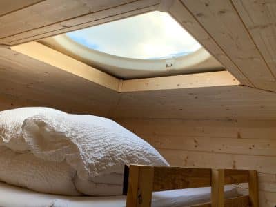 Cabane en bois avec un velux offrant une vue sur le ciel, ambiance cosy et naturelle.