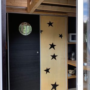 Hébergement insolite à Limousin : cabane moderne avec porte en bois décorée détoiles.
