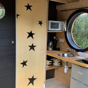 Hébergement insolite en Limousin : charmante tiny house avec porte étoilée et kitchenette.
