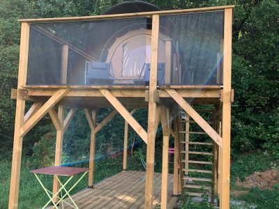Hébergement insolite en cabane sur pilotis, avec terrasse en bois et vue sur la nature.