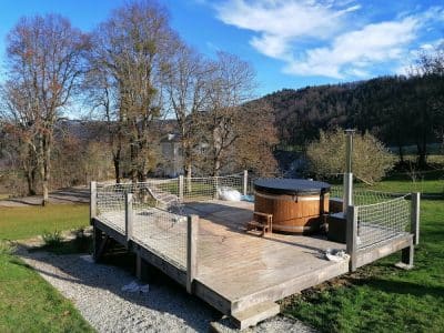 Hébergement insolite en Auvergne-Rhône-Alpes avec jacuzzi sur une terrasse en bois.
