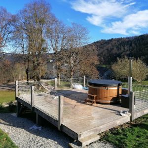 Hébergement insolite en Auvergne-Rhône-Alpes avec terrasse en bois et jacuzzi.