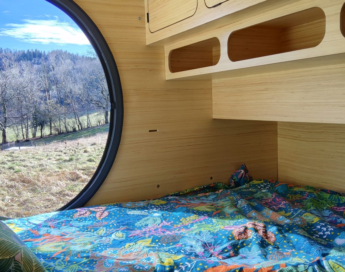 Hébergement insolite en bulle avec vue panoramique sur la nature et literie colorée.