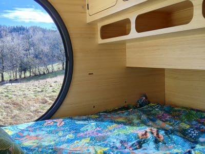 Hébergement insolite en bulle avec vue panoramique sur la nature et literie colorée.
