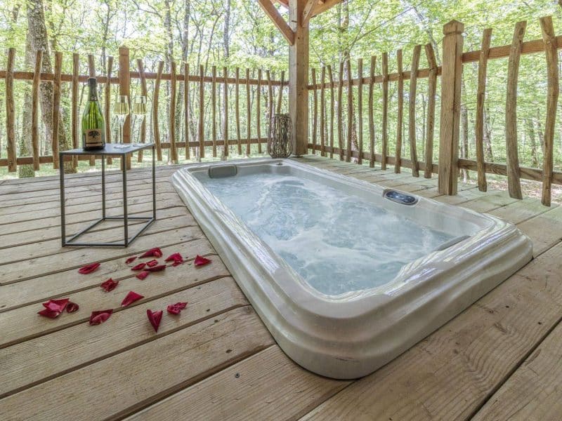 Cabane romantique en pleine nature avec jacuzzi et vue sur la forêt.
