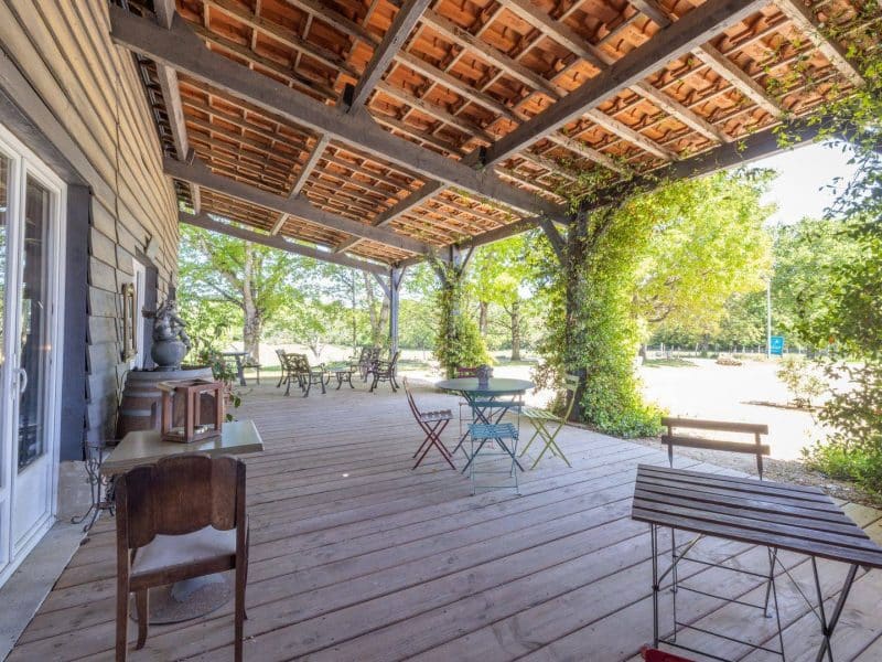 Charmante maison dhôtes avec terrasse en bois, entourée de verdure.