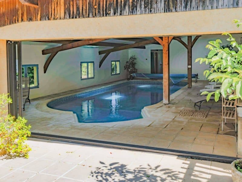Maison de vacances avec piscine intérieure et poutres apparentes, ambiance relaxante.
