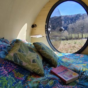 Hébergement insolite en bulle avec vue sur la nature et literie colorée.