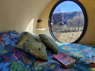 Hébergement insolite en bulle avec vue sur la nature et literie colorée.