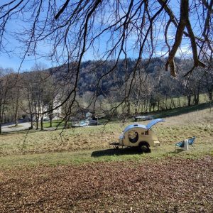 Hébergement insolite en caravane, entouré de verdure et sous un ciel bleu.