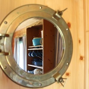 Hébergement insolite en Limousin : intérieur en bois avec miroir rond et vaisselle colorée.