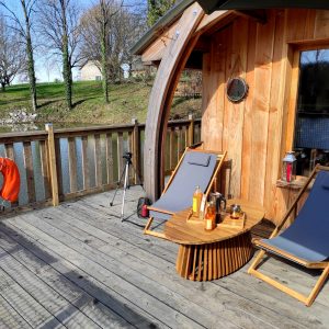 Hébergement insolite en bois au bord de leau, avec chaises longues et vue paisible.