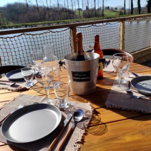 Table en bois avec vue sur leau, champagne prêt pour un séjour en cabane insolite.