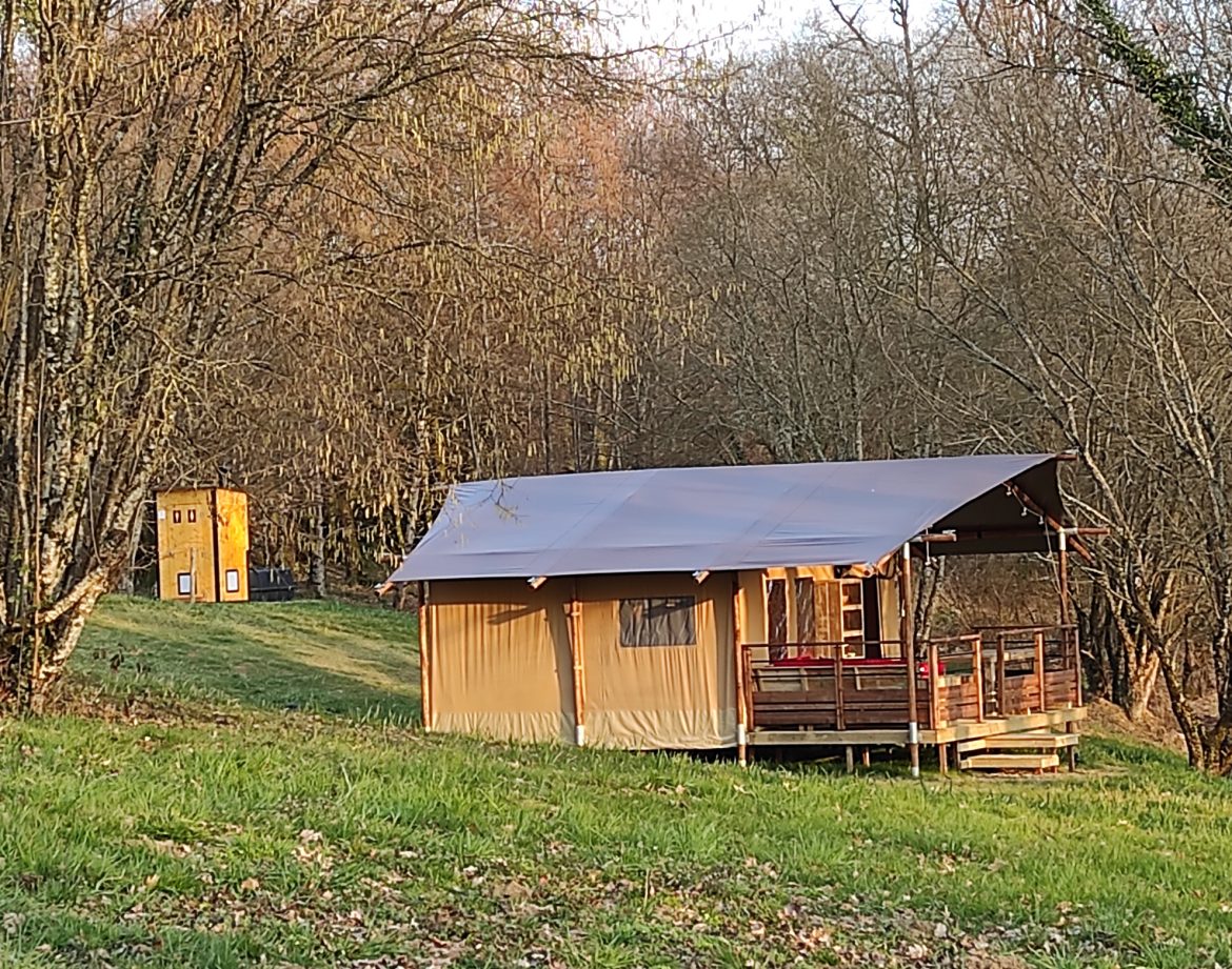 Tente safari en Limousin, entourée darbres, avec une terrasse en bois accueillante.