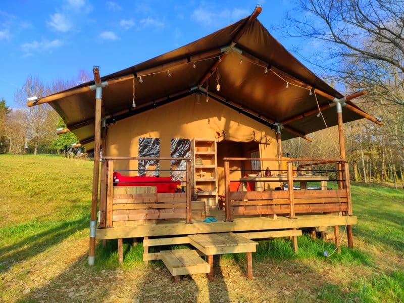 Cabane en toile à Limousin, avec terrasse en bois et vue sur la nature environnante.