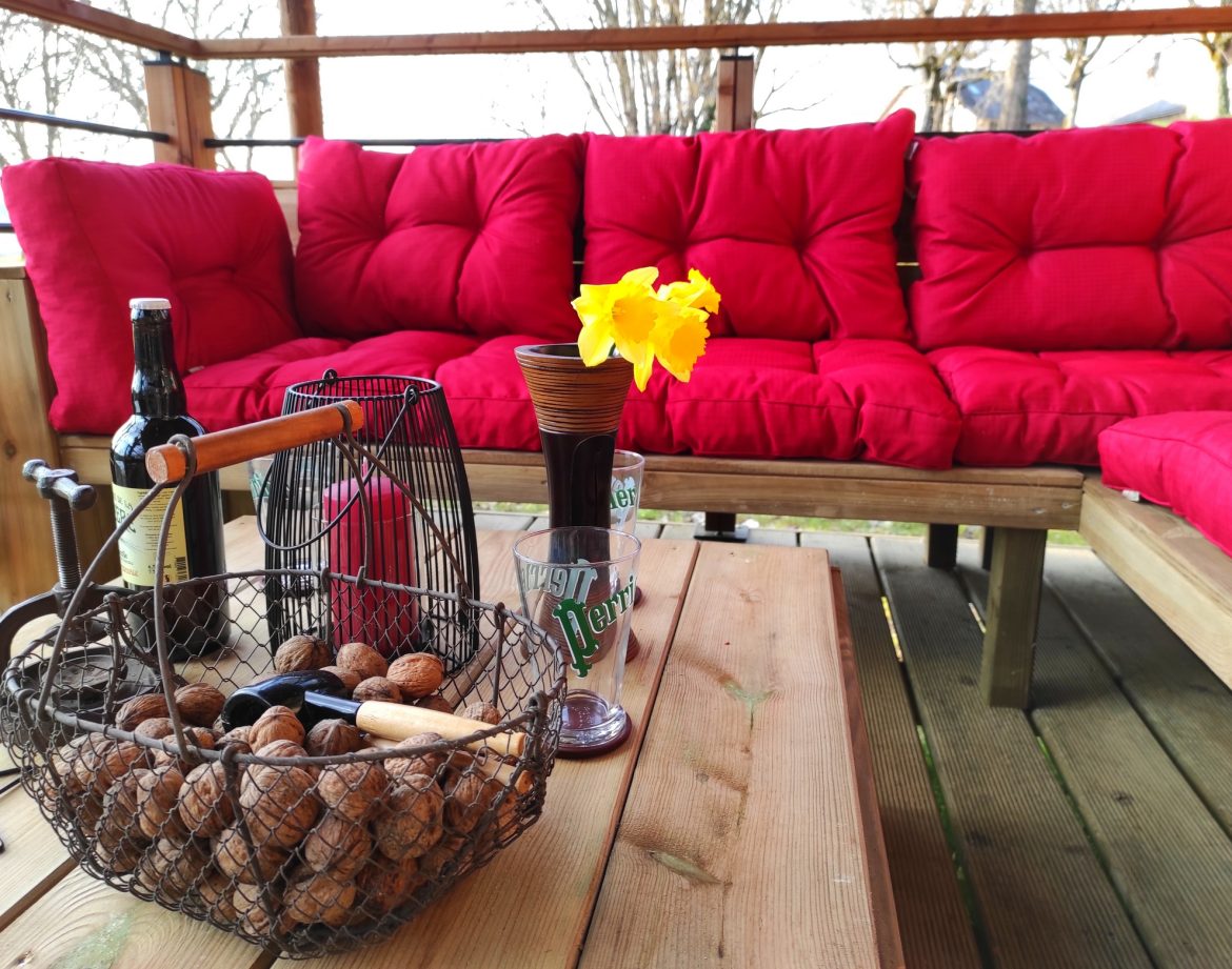 Hébergement insolite à Limousin : salon extérieur avec coussins rouges et décor chaleureux.