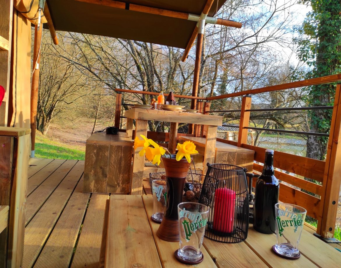Cabane en bois au bord de leau, avec terrasse en bois et décor floral.