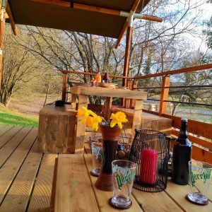 Cabane en bois au bord de leau, avec terrasse en bois et décor floral.