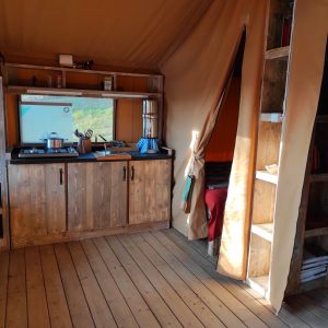 Tente safari moderne à Limousin, avec cuisine en bois et lit douillet.