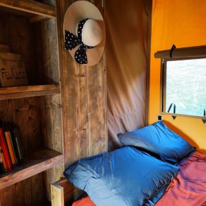 Cabane insolite à Limousin, avec des coussins moelleux et une étagère en bois.