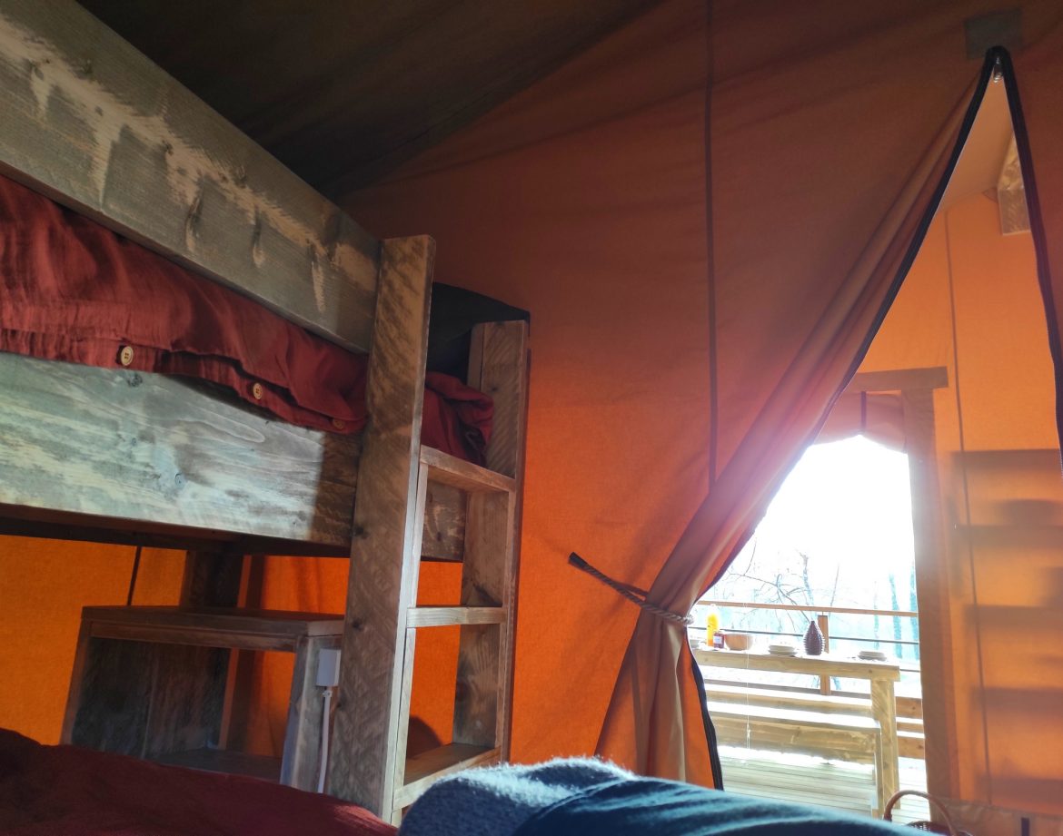 Hébergement insolite en tente avec lits superposés et vue sur la nature.