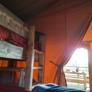 Hébergement insolite en tente avec lits superposés et vue sur la nature.