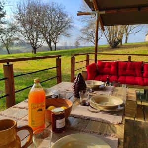 Hébergement insolite en Limousin : terrasse en bois avec vue sur la nature et mobilier confortable.