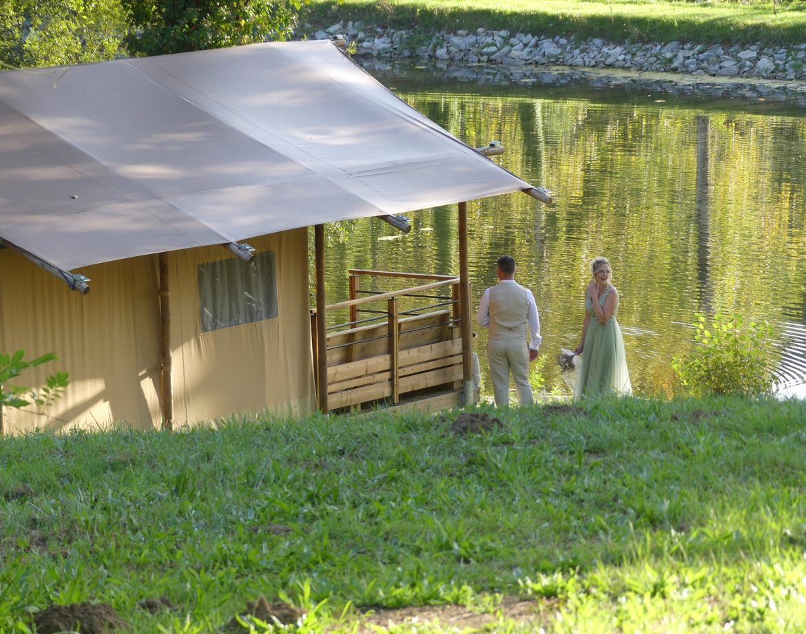 Hébergement insolite en tente près dun lac, avec un couple en tenue élégante.