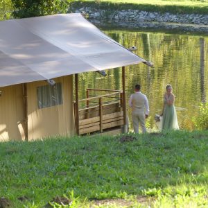Hébergement insolite en tente près dun lac, avec un couple en tenue élégante.