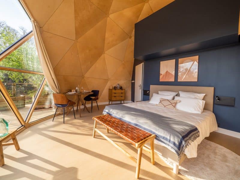 Chalet moderne avec murs en bois, lit confortable et vue sur la nature.
