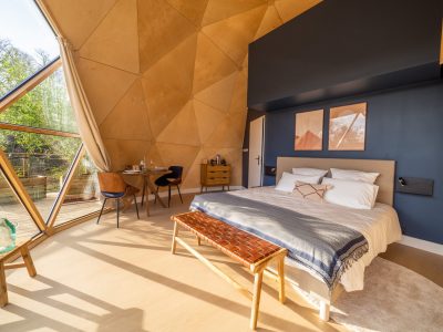 Dôme moderne en Auvergne, intérieur lumineux avec lit confortable et vue sur la nature.
