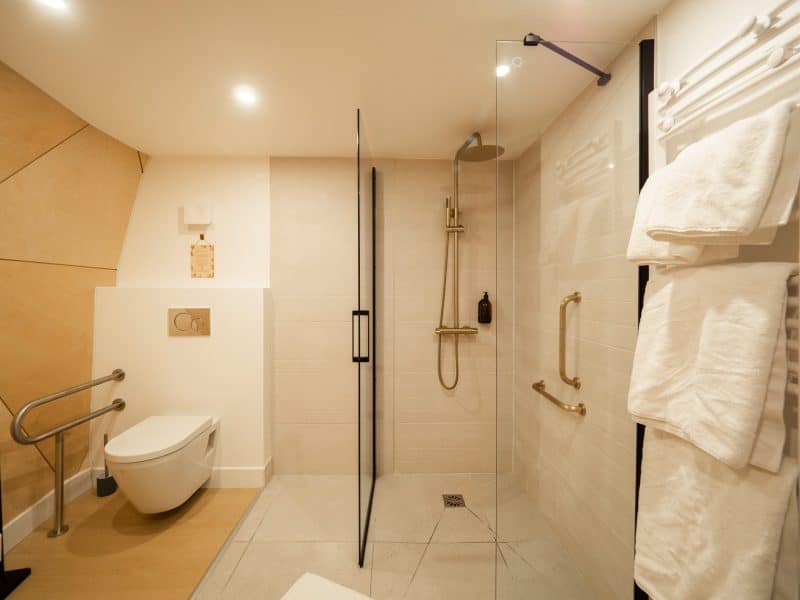 Salle de bain moderne dans un hôtel, avec douche à litalienne et décor épuré.