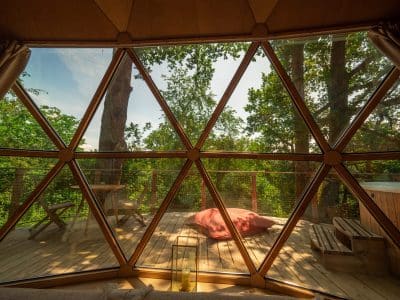 Dôme en bois avec vue sur la nature, terrasse en bois et coin détente.