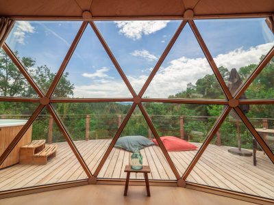 Dôme géodésique en Auvergne avec vue sur la nature et terrasse en bois.