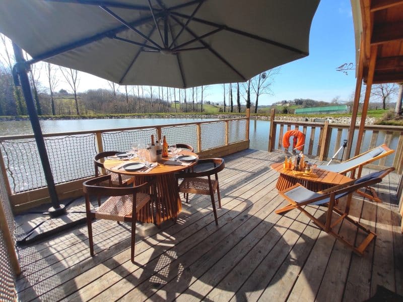 Chalet au bord de leau avec terrasse en bois et vue sur le lac.